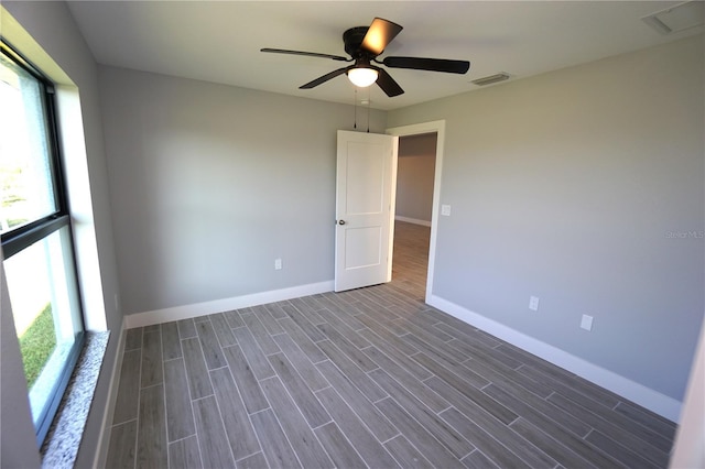 empty room with visible vents, baseboards, a ceiling fan, and wood tiled floor