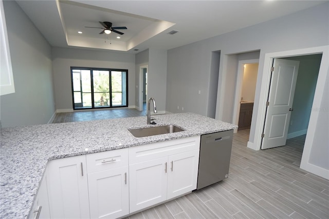 kitchen featuring wood finish floors, dishwasher, a tray ceiling, white cabinetry, and a sink