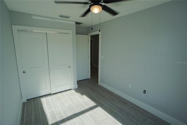 unfurnished bedroom with visible vents, a ceiling fan, a closet, baseboards, and wood tiled floor