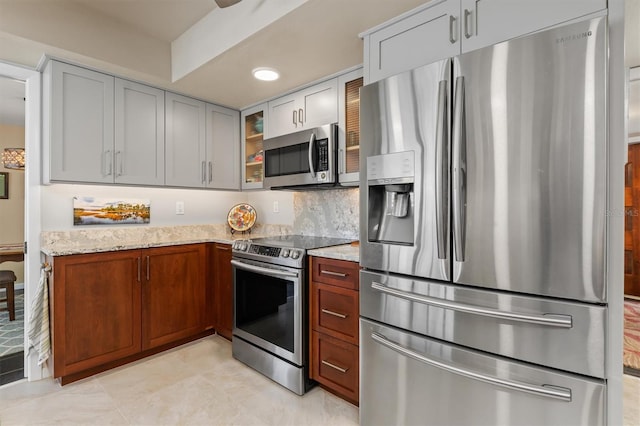 kitchen with appliances with stainless steel finishes, light stone counters, and decorative backsplash