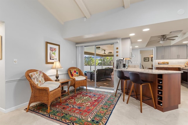 interior space with sink, gray cabinetry, a kitchen breakfast bar, ceiling fan, and light stone countertops