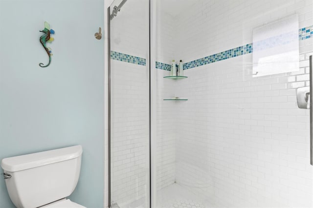 bathroom featuring a shower with door and toilet