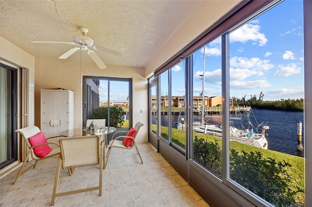 sunroom / solarium with ceiling fan and a water view