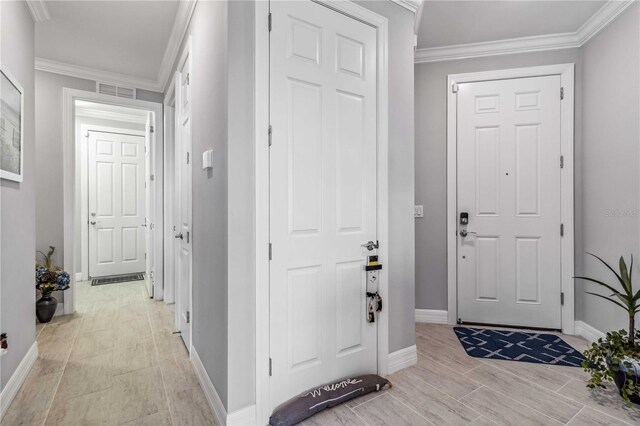 foyer entrance with light hardwood / wood-style flooring and ornamental molding