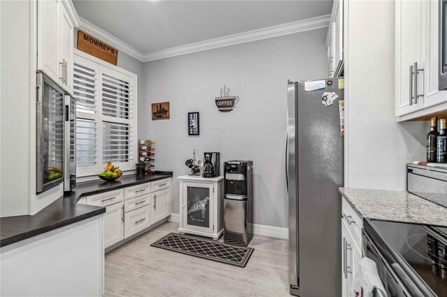 kitchen featuring stainless steel refrigerator, light tile patterned floors, dark stone counters, white cabinets, and ornamental molding