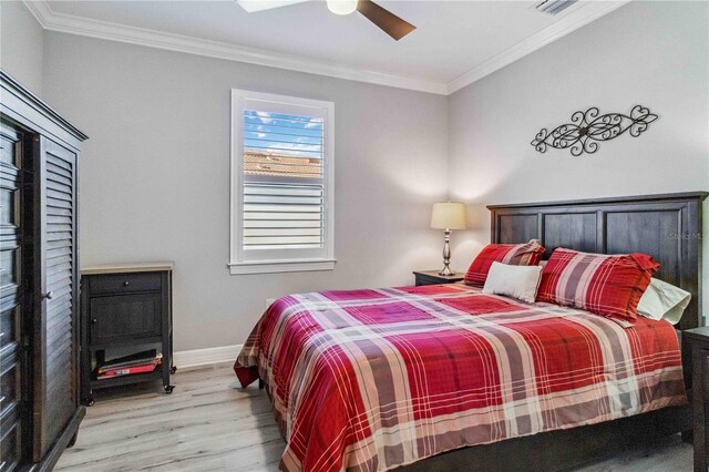 bedroom featuring light hardwood / wood-style floors, ceiling fan, and crown molding