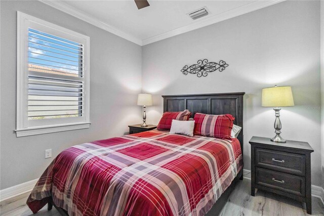 bedroom with wood-type flooring, multiple windows, ornamental molding, and ceiling fan