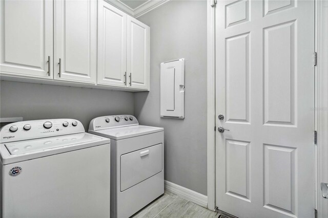 clothes washing area featuring washer and clothes dryer, cabinets, light wood-type flooring, and crown molding