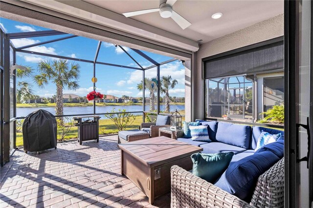 view of patio featuring a lanai, an outdoor living space, a water view, and ceiling fan