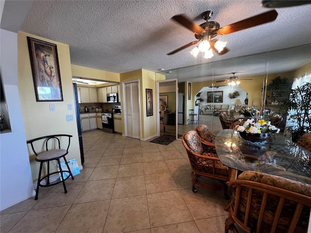 tiled dining space featuring a textured ceiling and ceiling fan