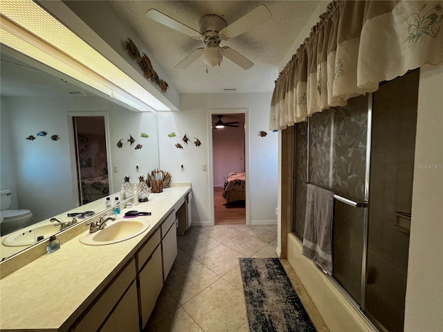 full bathroom with tile patterned flooring, bath / shower combo with glass door, a textured ceiling, toilet, and vanity