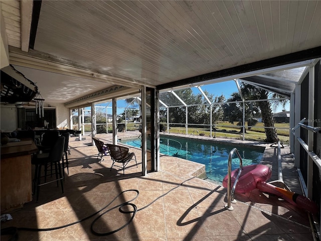 view of swimming pool featuring a lanai, a patio area, and a bar