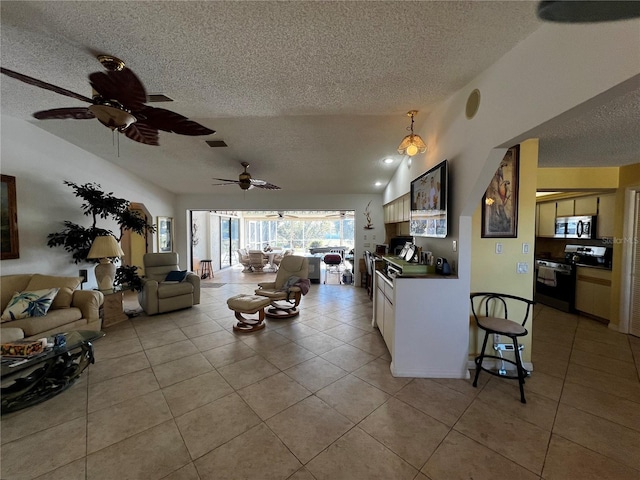 living room featuring vaulted ceiling, ceiling fan, light tile patterned flooring, and a textured ceiling