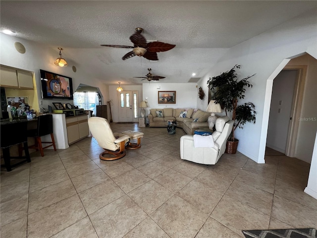 living room with a textured ceiling, vaulted ceiling, ceiling fan, and light tile patterned flooring