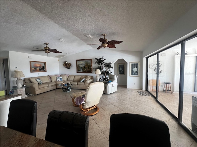 living room with a textured ceiling, ceiling fan, light tile patterned flooring, and vaulted ceiling