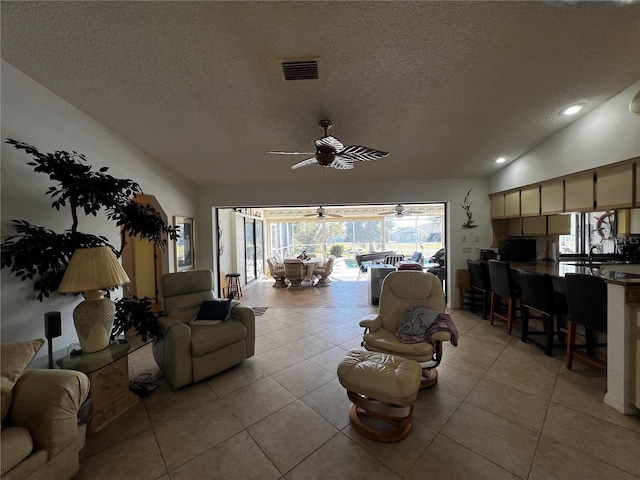 tiled living room with ceiling fan, lofted ceiling, and a textured ceiling