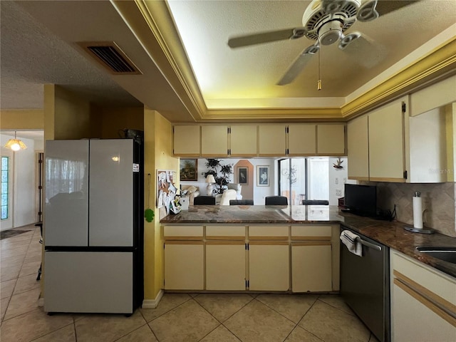 kitchen featuring cream cabinets, light tile patterned floors, white fridge, and stainless steel dishwasher