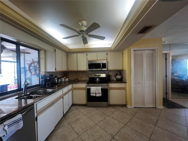 kitchen featuring tasteful backsplash, sink, light tile patterned floors, and appliances with stainless steel finishes