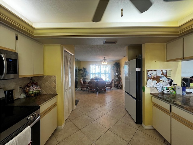 kitchen with ceiling fan, tasteful backsplash, cream cabinets, light tile patterned floors, and appliances with stainless steel finishes