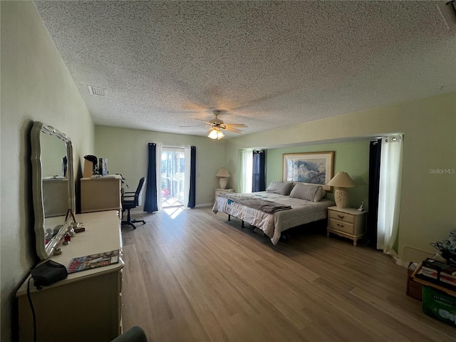 bedroom featuring access to outside, ceiling fan, a textured ceiling, and hardwood / wood-style flooring