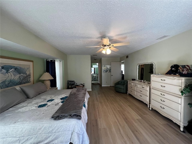 bedroom with ceiling fan, light hardwood / wood-style flooring, and a textured ceiling