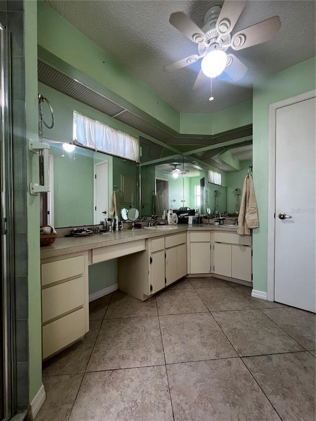 bathroom featuring a textured ceiling, vanity, tile patterned floors, and a shower with shower door