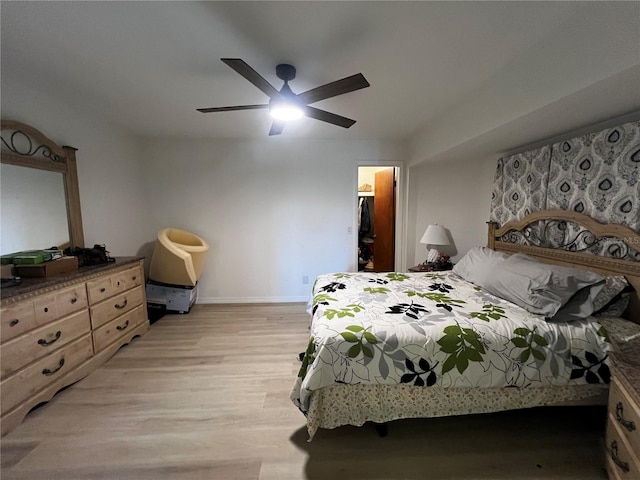 bedroom with a walk in closet, ceiling fan, a closet, and light wood-type flooring