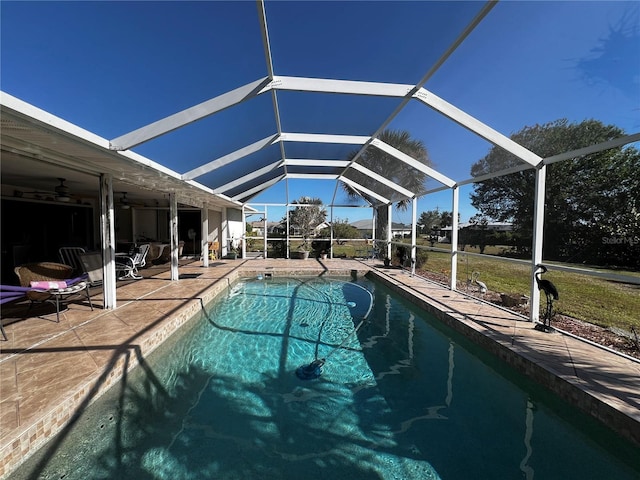 view of swimming pool featuring glass enclosure, ceiling fan, and a patio