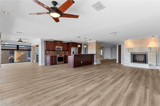 unfurnished living room with sink, light hardwood / wood-style flooring, ceiling fan, and a tiled fireplace