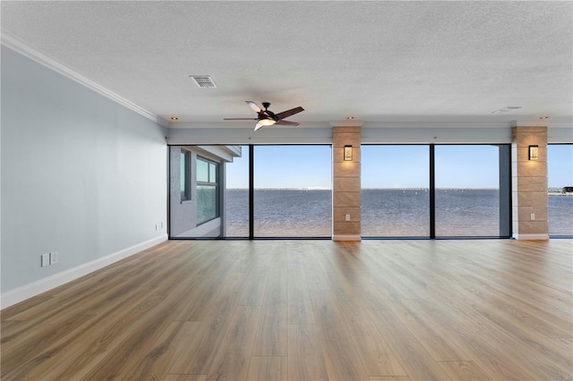 unfurnished room featuring crown molding, a water view, wood-type flooring, and ceiling fan