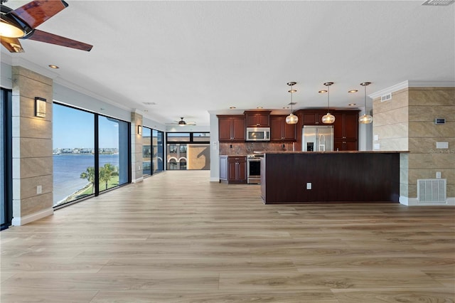 kitchen with a water view, hanging light fixtures, light hardwood / wood-style flooring, ceiling fan, and appliances with stainless steel finishes