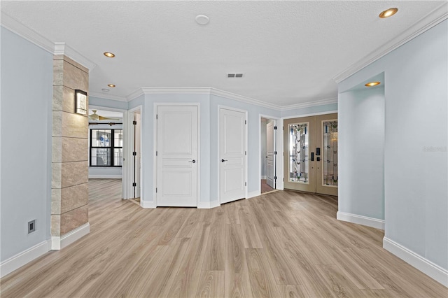 empty room featuring crown molding, french doors, light hardwood / wood-style floors, and a textured ceiling