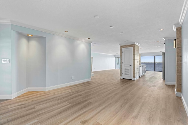 unfurnished room featuring a textured ceiling, light wood-type flooring, and crown molding