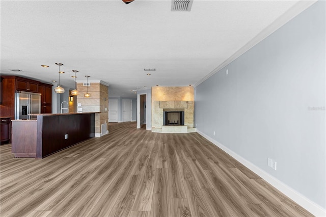 unfurnished living room with ornamental molding, a textured ceiling, sink, wood-type flooring, and a fireplace