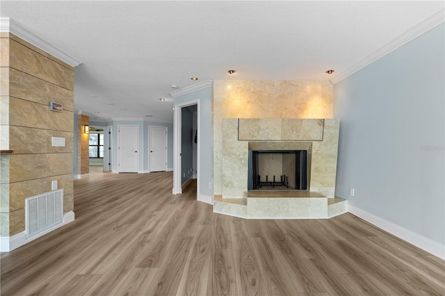 unfurnished living room with ornamental molding, tile walls, a textured ceiling, wood-type flooring, and a tiled fireplace