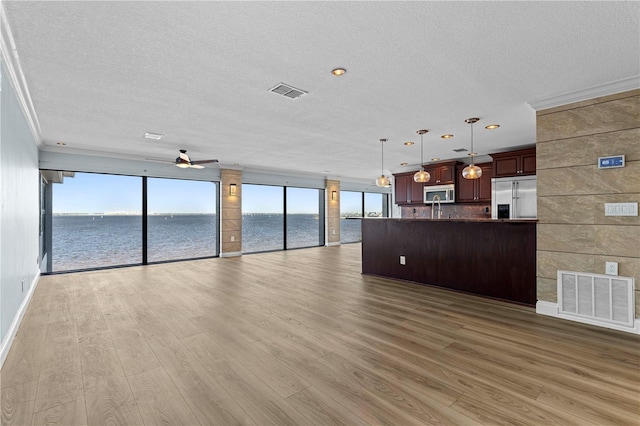 unfurnished living room with a water view, crown molding, light hardwood / wood-style flooring, ceiling fan, and a textured ceiling