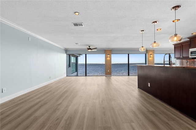 unfurnished living room featuring a water view, crown molding, ceiling fan, and light hardwood / wood-style floors