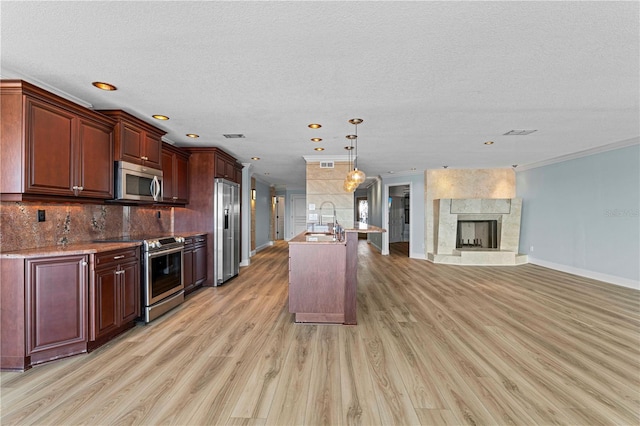 kitchen featuring sink, light hardwood / wood-style flooring, a fireplace, appliances with stainless steel finishes, and ornamental molding