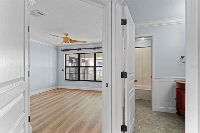 hall with a textured ceiling, light wood-type flooring, and crown molding