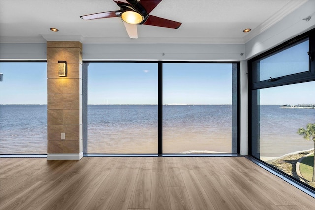 interior space with hardwood / wood-style floors, a water view, ceiling fan, and crown molding