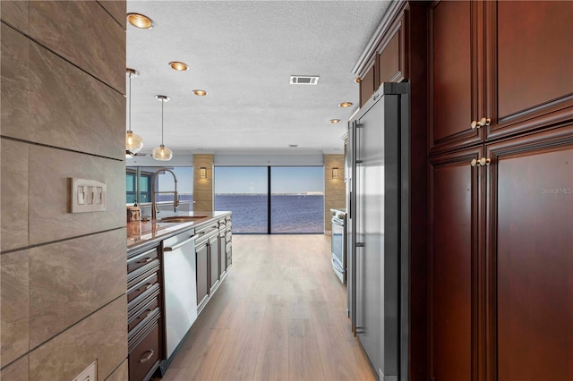 1600 W Marion Ave Unit 234, Punta Gorda, FL 33950 - kitchen with appliances with stainless steel finishes, light wood-style floors, a textured ceiling, decorative light fixtures, and a water view
