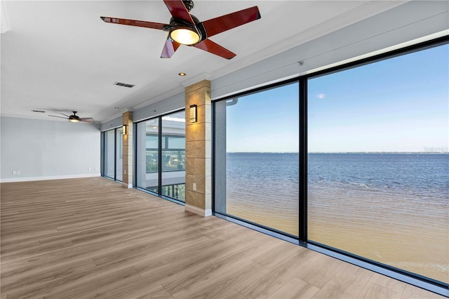 empty room with hardwood / wood-style floors, a water view, ceiling fan, and crown molding