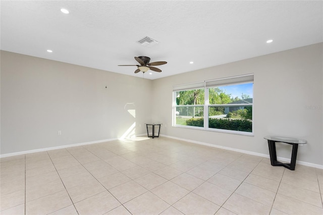 tiled empty room with ceiling fan and a textured ceiling