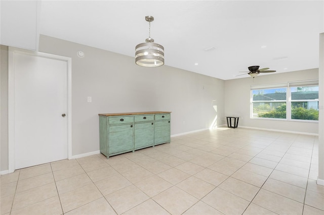 tiled empty room with ceiling fan with notable chandelier