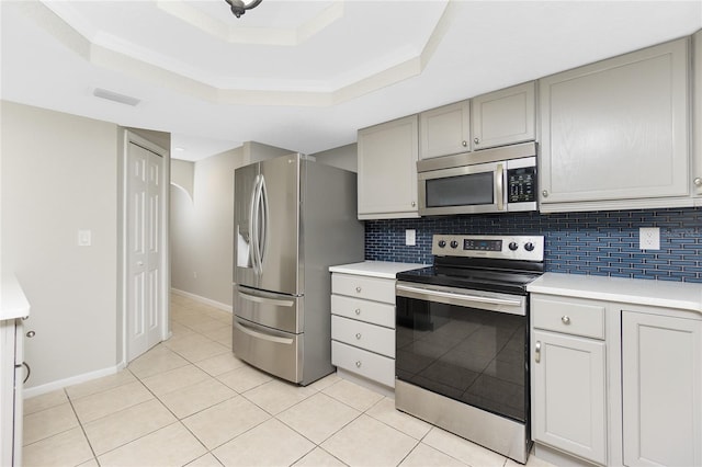 kitchen featuring tasteful backsplash, light tile patterned floors, a raised ceiling, and appliances with stainless steel finishes