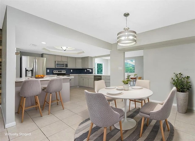 1190 Victoria Ave NW, Port Charlotte, FL 33948 - dining space with light tile patterned flooring, a tray ceiling, and baseboards