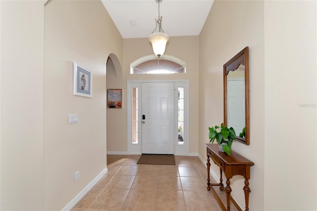 foyer entrance featuring a towering ceiling and light tile patterned floors