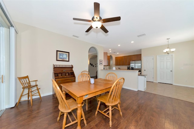 dining space with ceiling fan with notable chandelier and dark hardwood / wood-style flooring