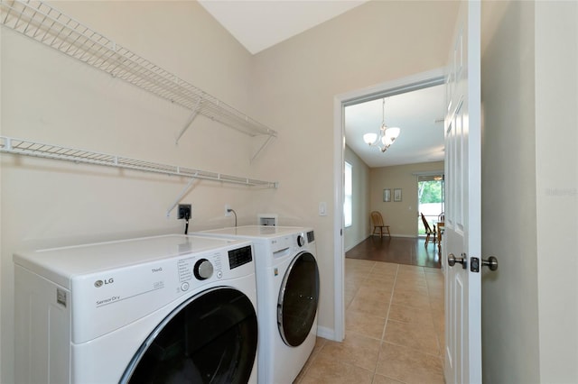 laundry room with washer and clothes dryer, light tile patterned flooring, and a chandelier