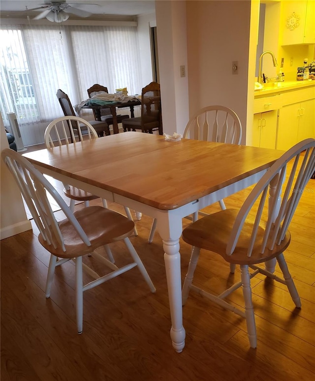 dining space featuring ceiling fan, sink, and wood-type flooring